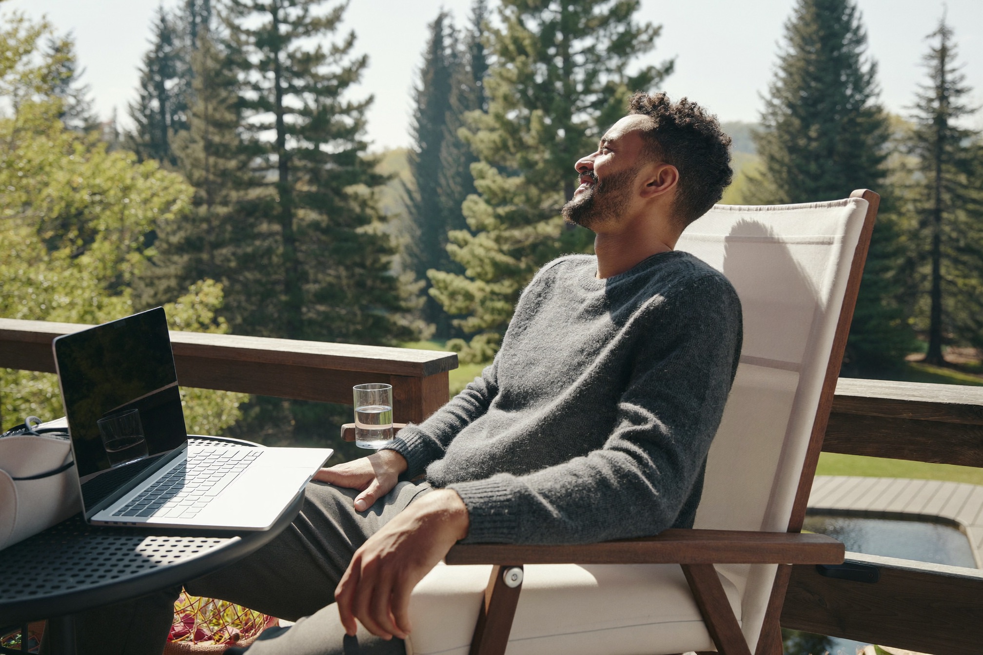 A relaxed professional on a deck, laptop closed beside him